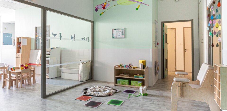Crèche Annecy Ombrelles & Casquettes people&baby salle de vie jeux enfants tables chaises en bois livres